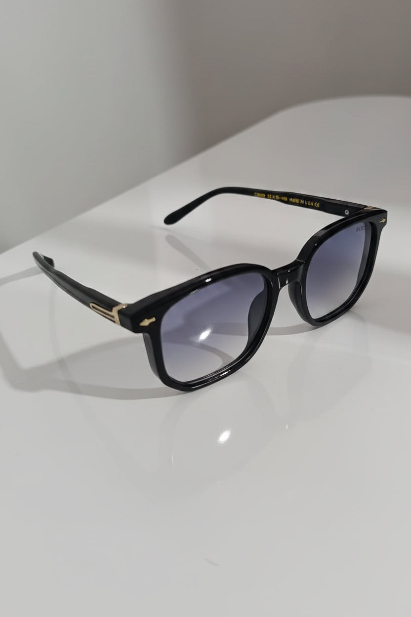 Black sunglasses with gold accents on a white surface