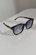 Black sunglasses with gold accents on a white surface