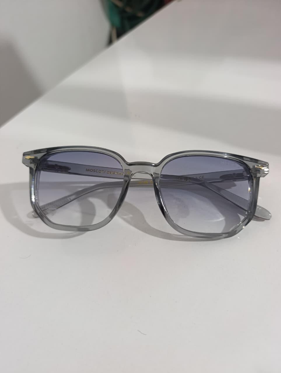 Sunglasses with a clear frame on a white surface