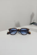 Sunglasses with tortoiseshell frame and blue lenses on a white surface